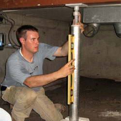 A contractor in Fort Knox installing a crawl space jack post.