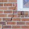 long jagged cracks starting at the corner of a window along a brick wall on a Brandenburg home
