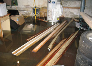 A severely flooding basement in Washington, with lumber and personal items floating in a foot of water