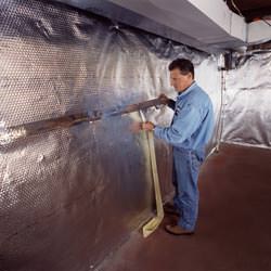 Installation of a radiant heat and vapor barrier on a basement wall in Petersburg