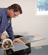 installing a waterproof vapor barrier on a basement floor to prepare for basement carpeting in a Henderson home